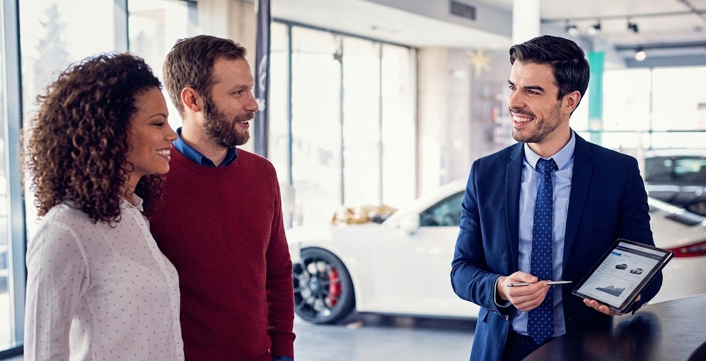 Consultor a atender um casal num stand automóvel